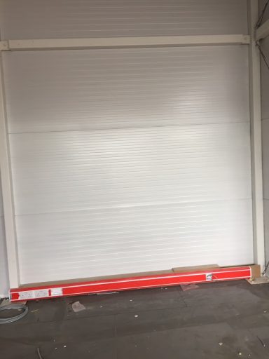 Kingspan Cladding: After A closed white roller door with a red base at the bottom.