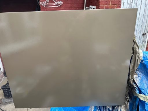 Sheffield University: Panels After Smooth, matte brown surface on a background with blue tarpaulin and brick wall.